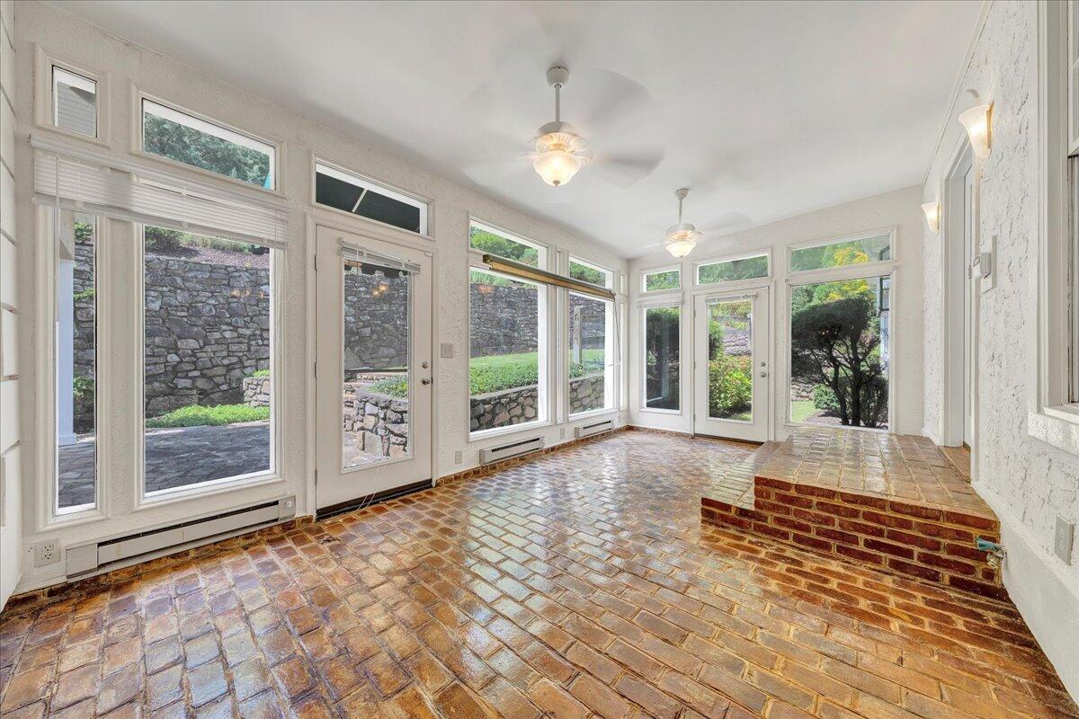 Bright sunroom with a glossy brick floor, walls of windows, and a raised brick platform.