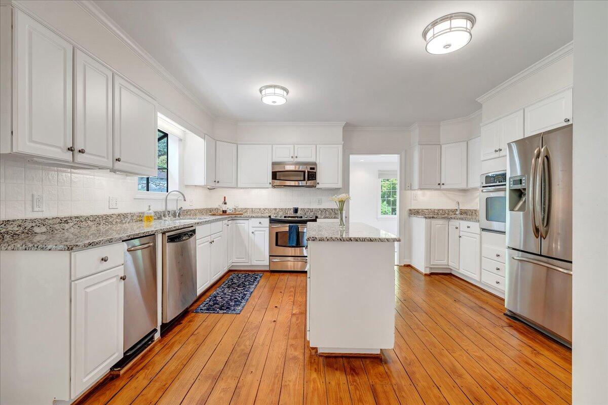 Kitchen with white cabinets, granite counters, stainless steel appliances, and a central island.