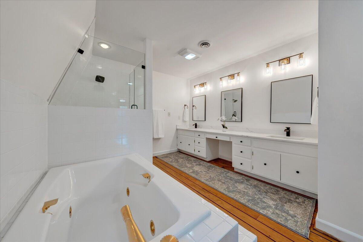 Bathroom with a jetted soaking tub, glass shower, and long double vanity.