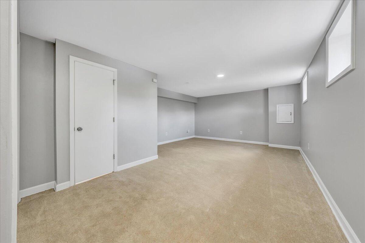 Empty carpeted room with gray walls, recessed lighting, and small high-set windows.