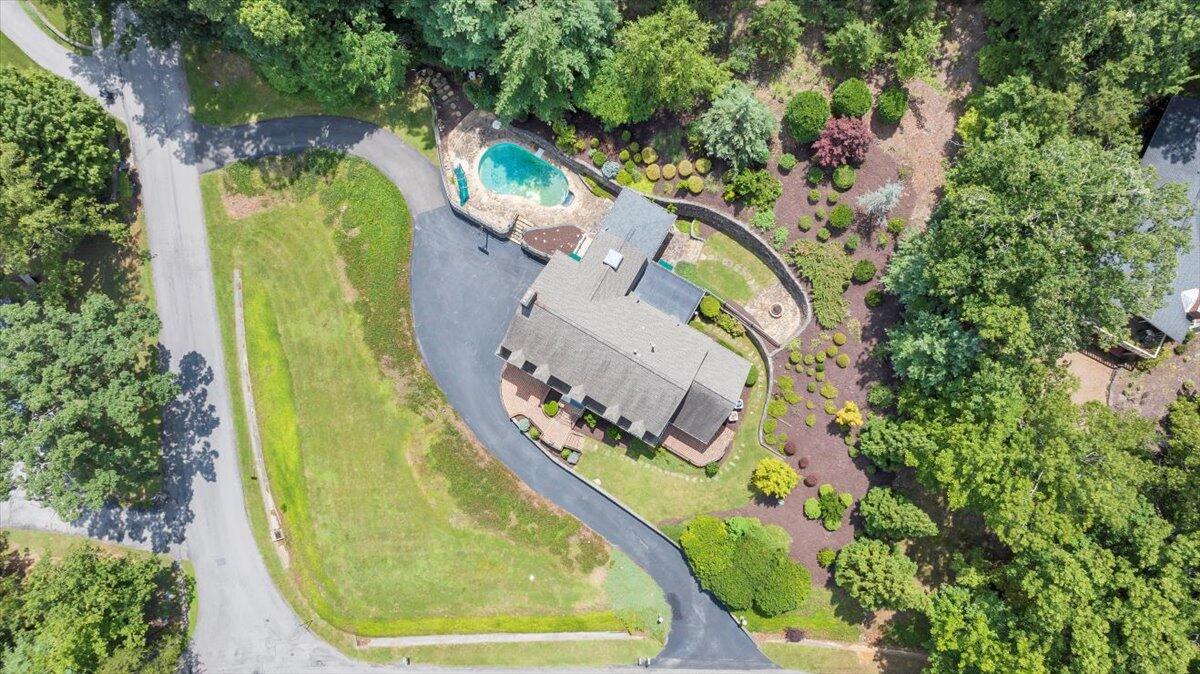 Aerial view of the home with a swimming pool, curved driveway, and landscaped grounds.