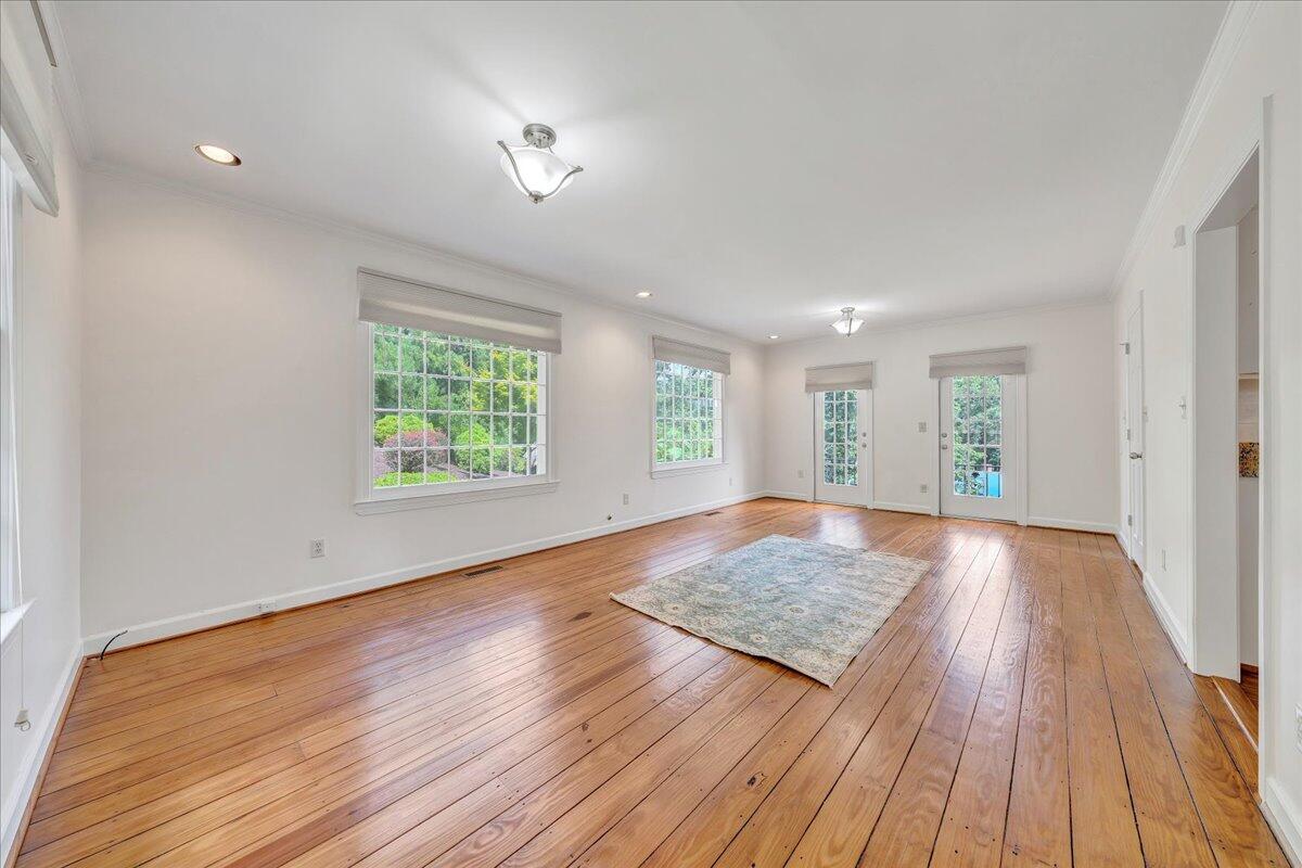 Bright living room with hardwood floors, large windows, glass doors, and a pale area rug.