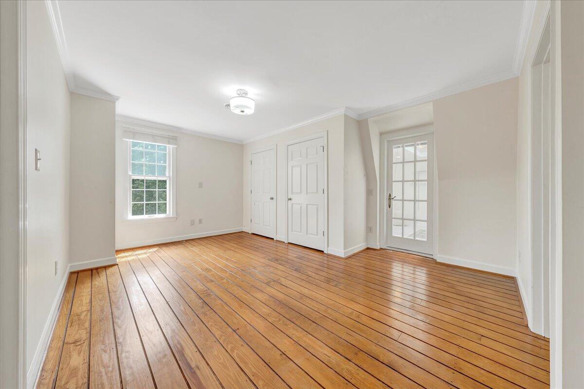 Empty room with polished hardwood floors, double closet doors, and a glass-paneled door.