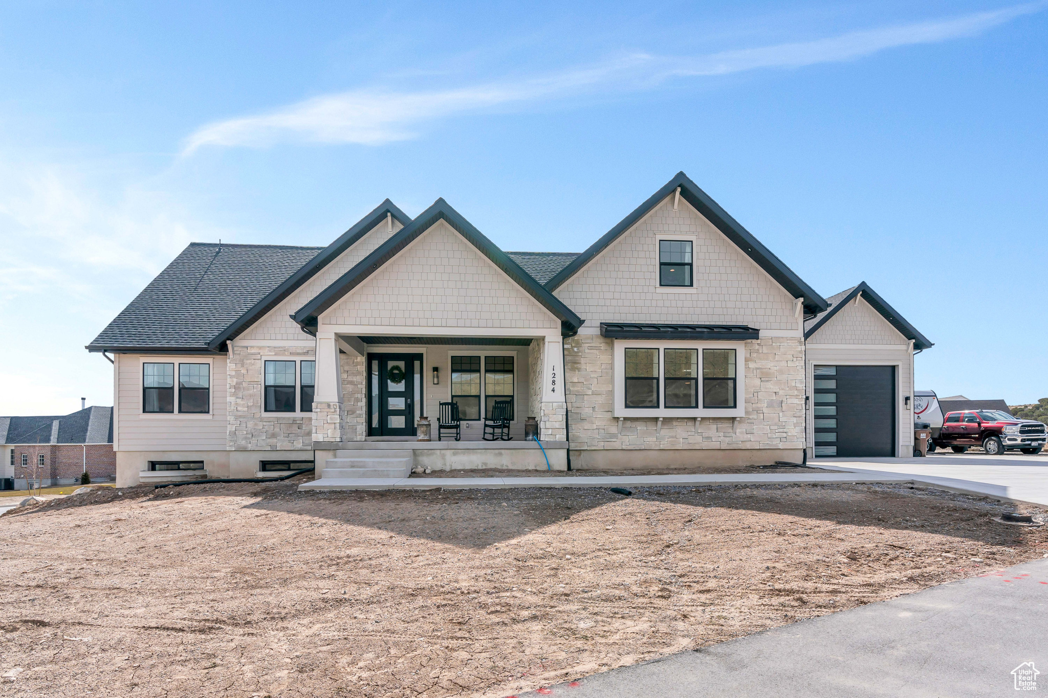 House exterior with stone accents, multiple gables, covered porch, and attached dark garage.