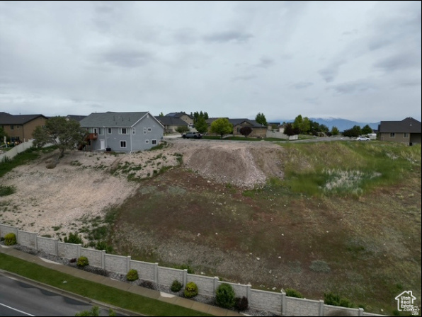Elevated view of a graded vacant lot bordered by neighboring homes and a concrete fence.
