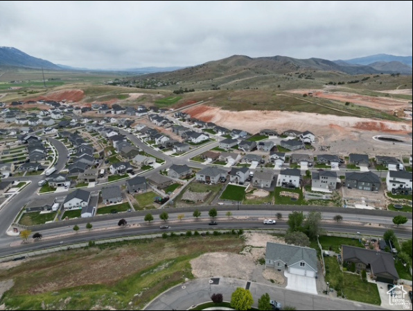 Aerial view of a residential neighborhood beside open land, with rolling hills and mountains in the distance.