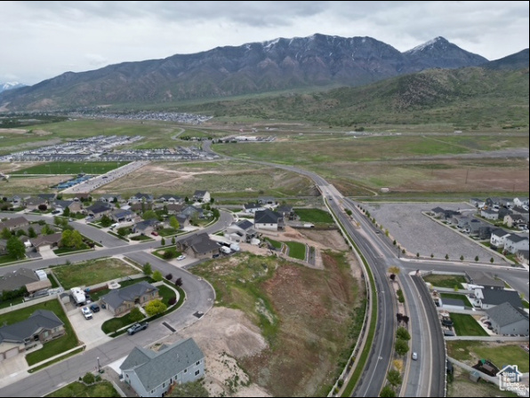 Aerial view of a residential neighborhood beside open land, with mountains in the background.