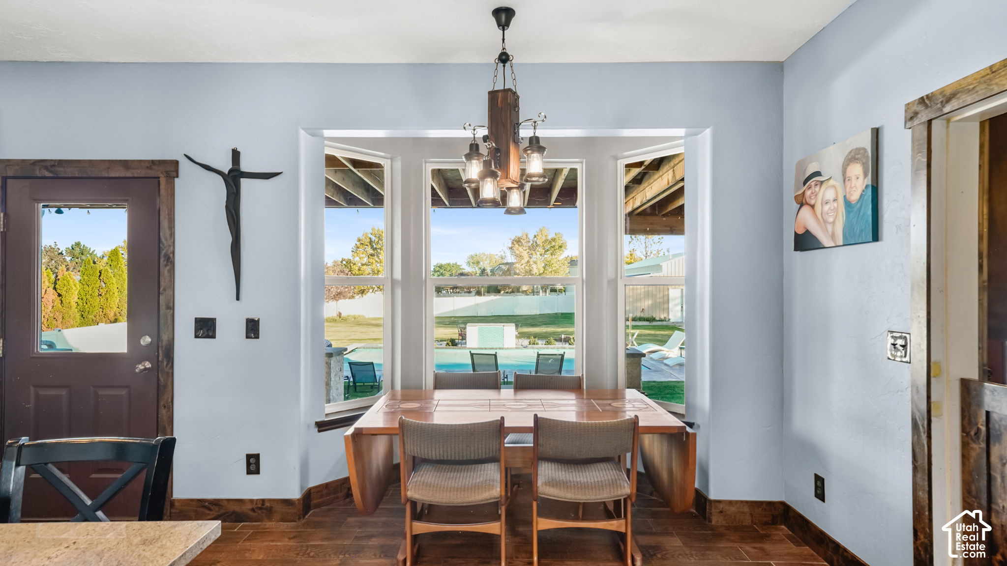 Dining room with a wooden table and chairs overlooking a backyard pool.