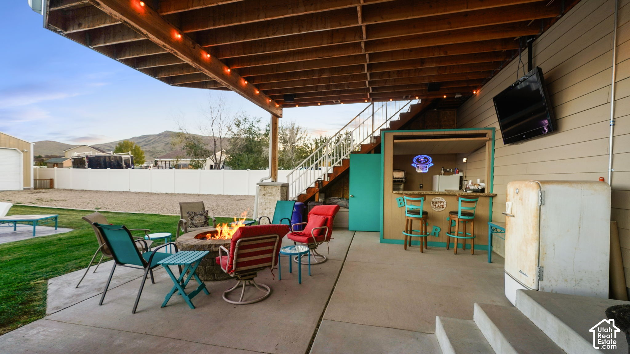 Covered backyard patio with a fire pit, colorful seating, and a turquoise-trimmed outdoor bar.