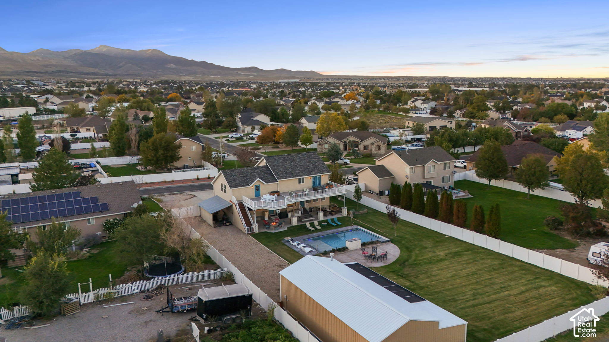 Aerial view of a home with a backyard pool and deck, surrounded by neighborhood homes and distant mountains.