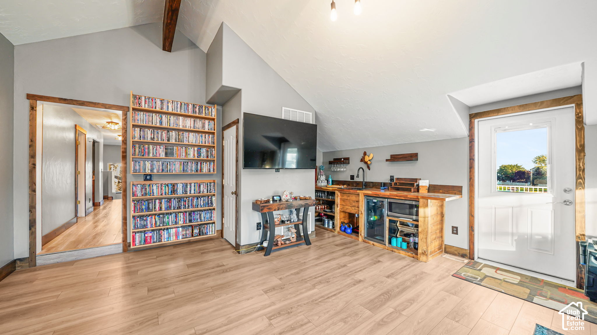 Entertainment room with a rustic wood wet bar, wall-mounted TV, and shelves of movies.