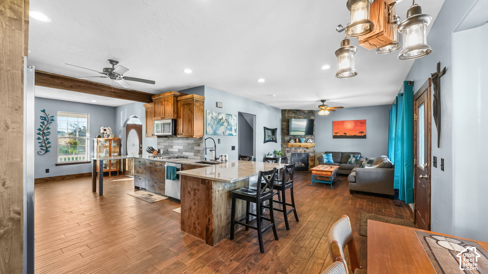 Open-plan kitchen and living room with a large wood-sided island and stone fireplace.