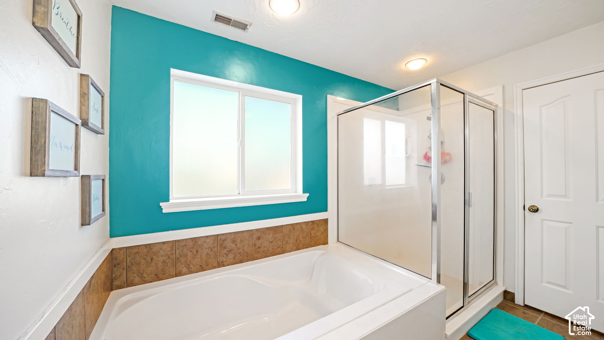 Bathroom with a white soaking tub, glass shower enclosure, and teal accent wall.