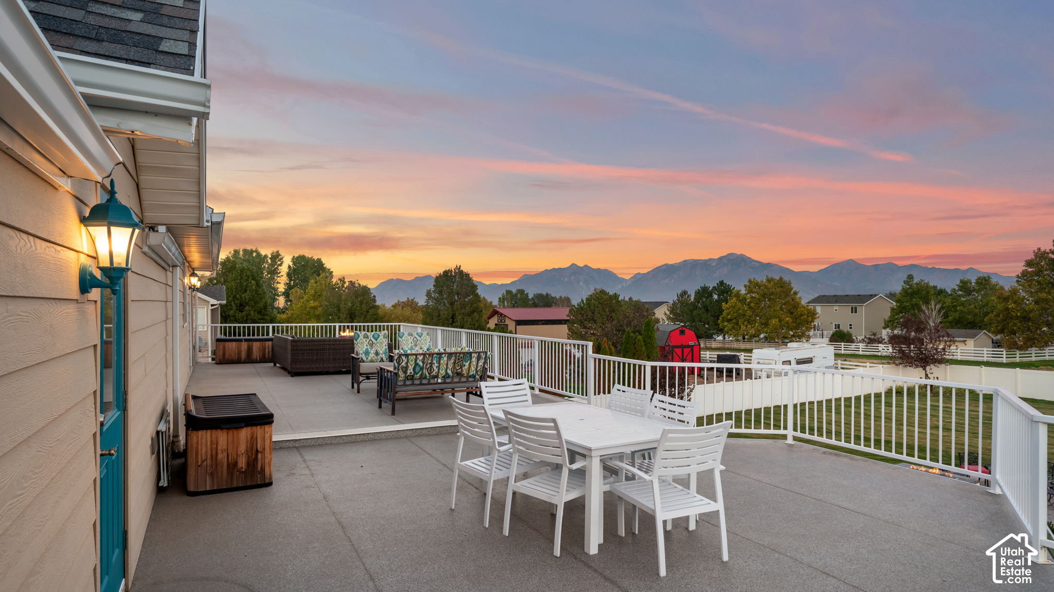 Outdoor patio with dining set and hot tub overlooking mountains at dusk.