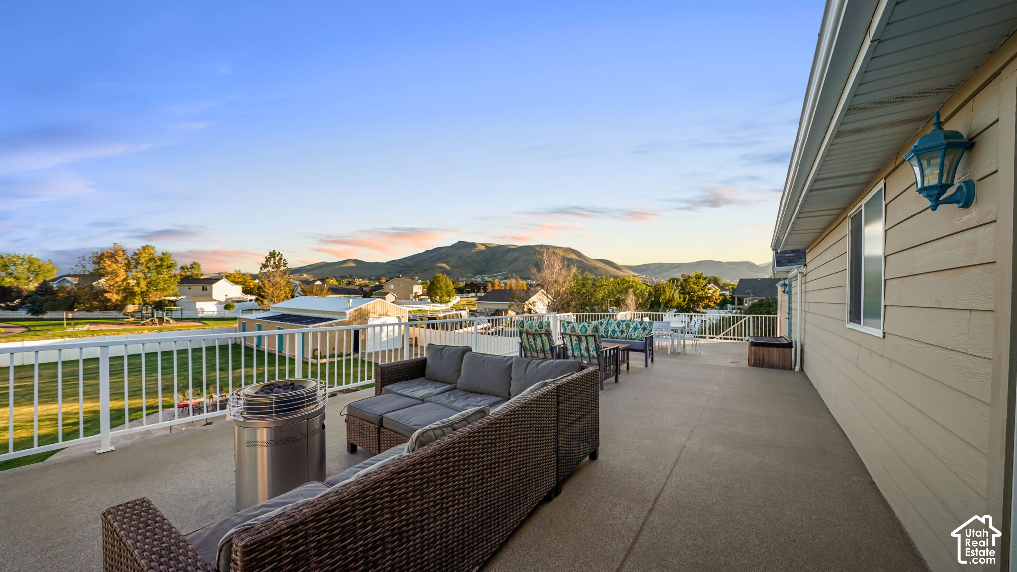 Furnished home deck with wicker seating and mountain views at sunset.