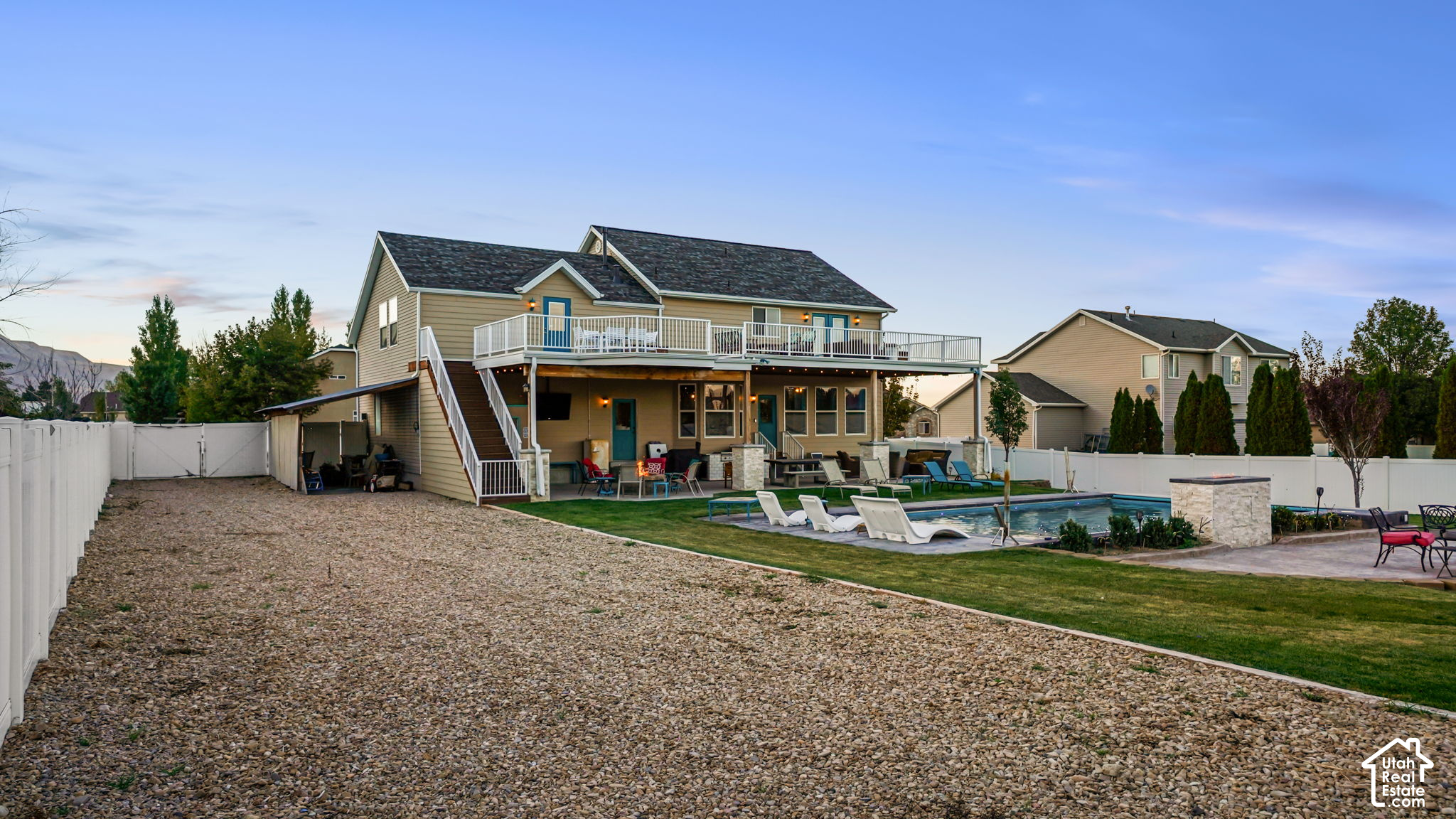 Two-story beige home with a raised deck, covered patio, and backyard swimming pool.