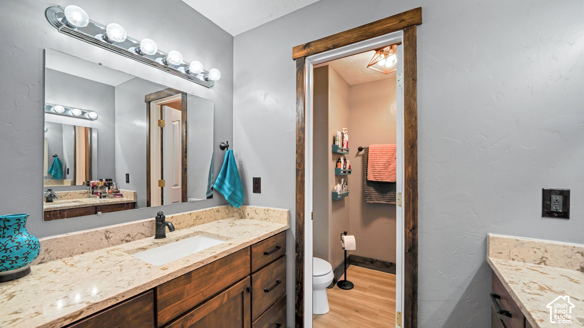 Bathroom with a granite vanity and dark wood cabinets, opening to a separate toilet area.
