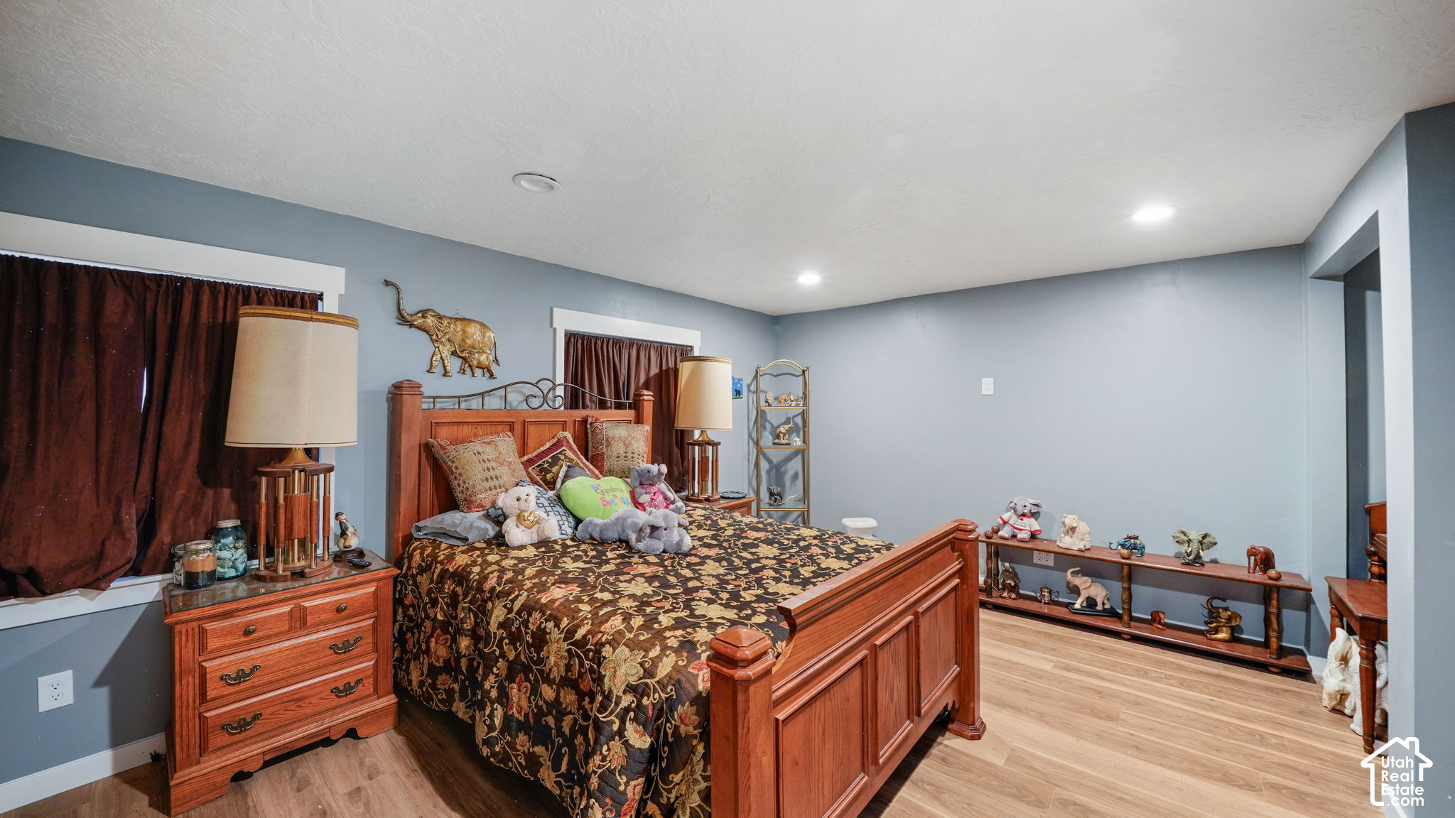 Bedroom with a large wooden bed, blue-gray walls, and light wood flooring.