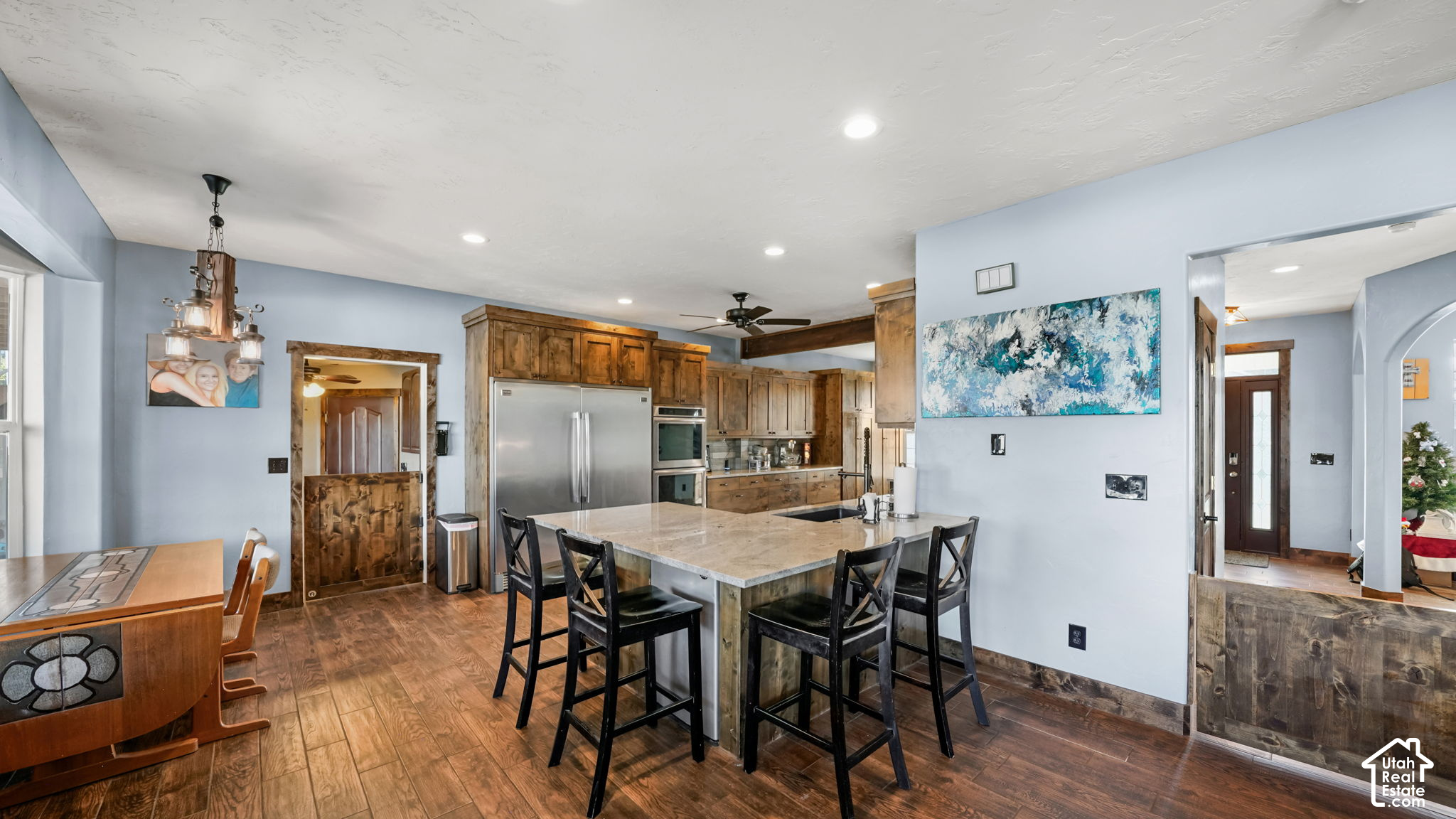 Kitchen with warm wood cabinets, stainless appliances, and a large island with bar stools.