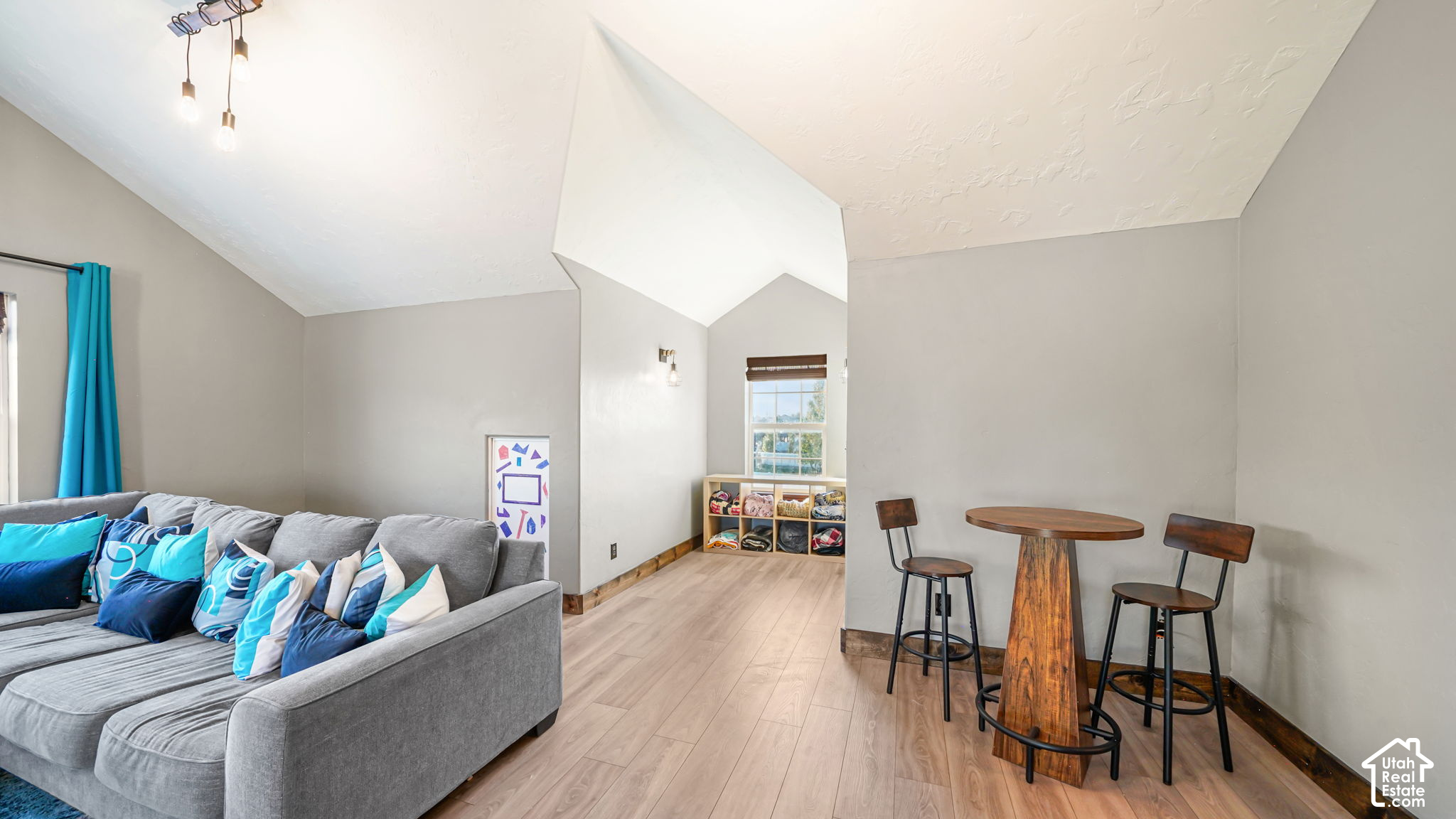 Living room with a vaulted ceiling, gray sectional sofa, and tall wooden table with stools.