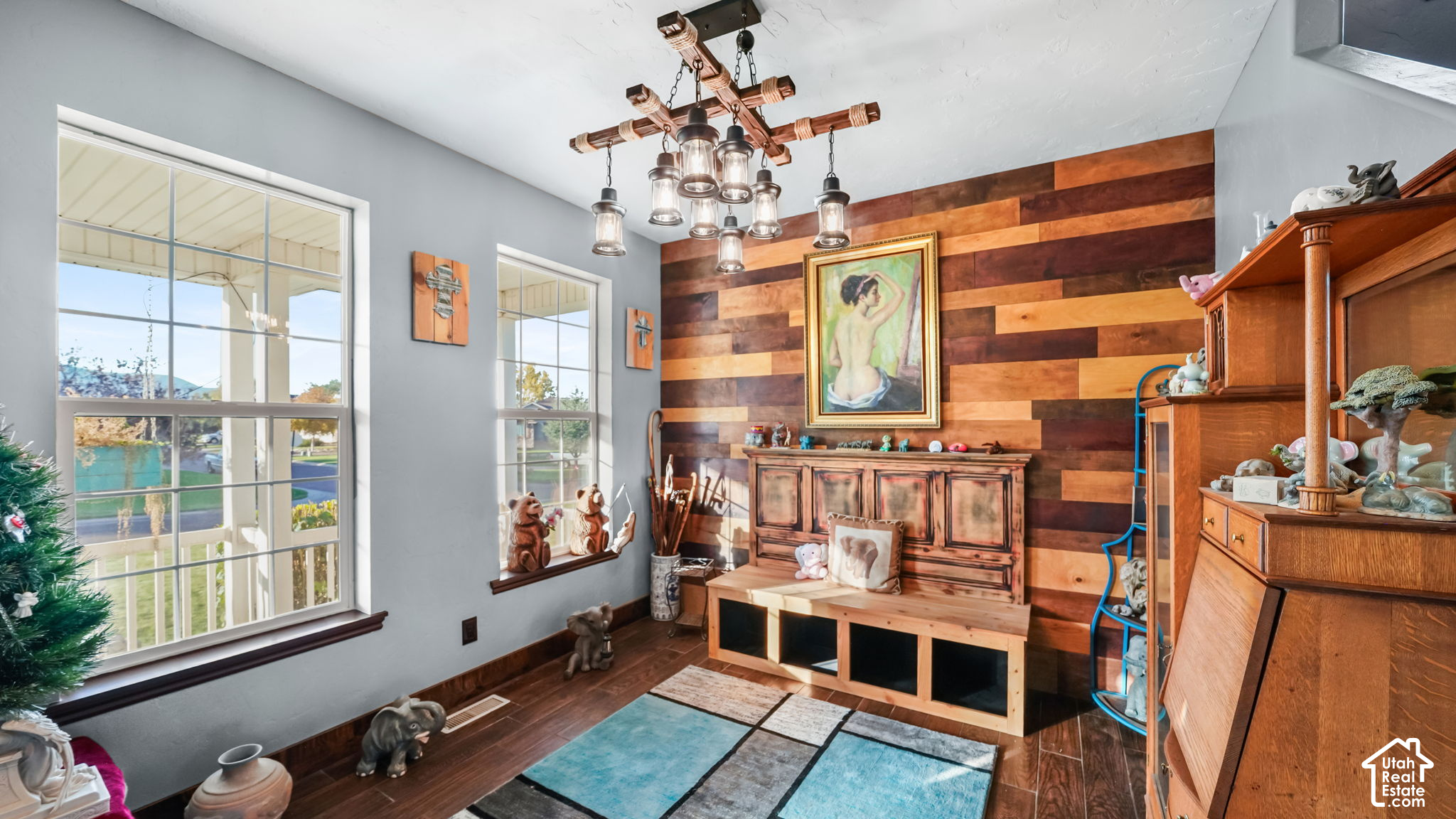 Living room with a colorful wood-plank accent wall, large windows, and rustic furnishings.