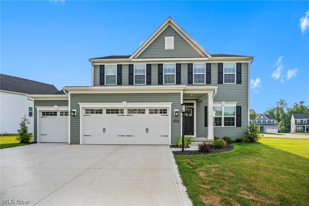 Two-story gray-green house with white trim, black shutters, and a three-car garage.