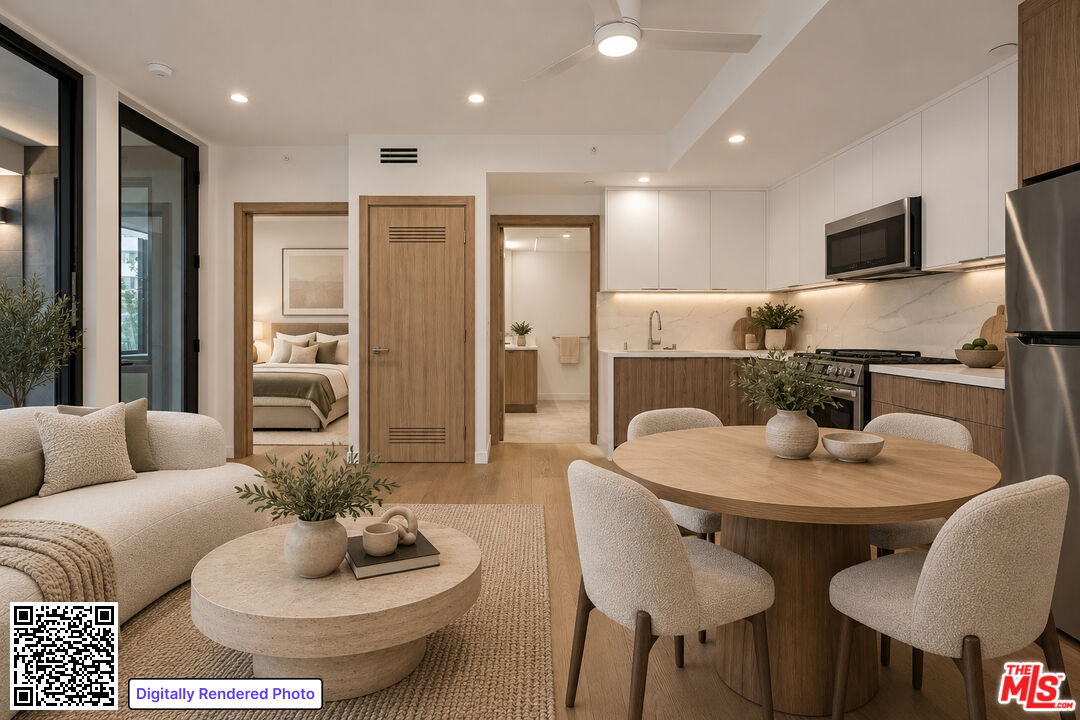 Open-plan living and dining area with a curved sofa, round table, and modern kitchen.