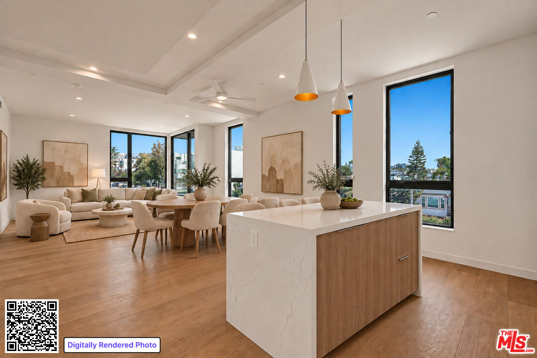 Open-plan kitchen and living room with a marble island, dining table, and large windows.