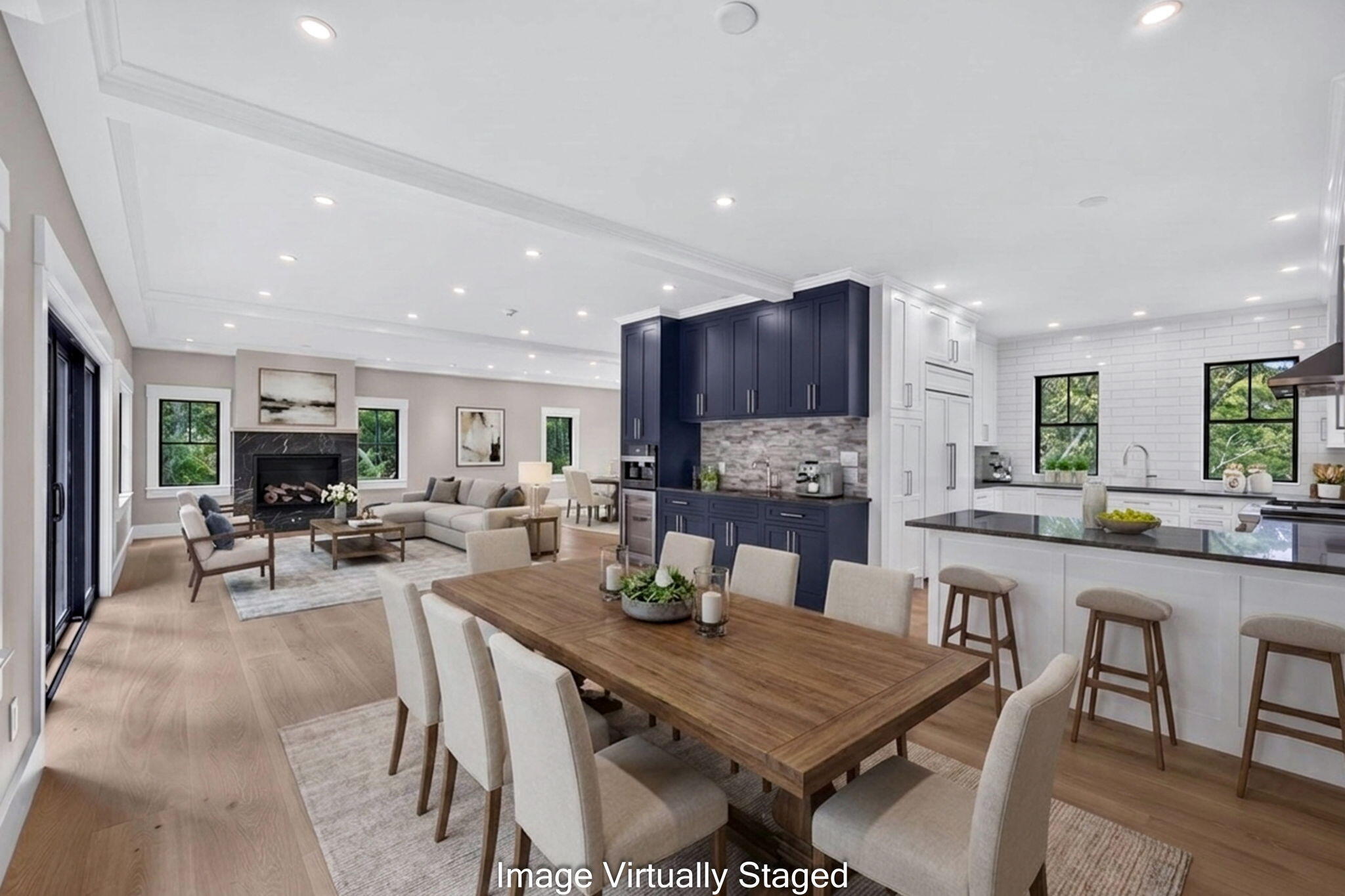 Open-plan kitchen, dining room, and living area with navy cabinets, a wood table, and fireplace.