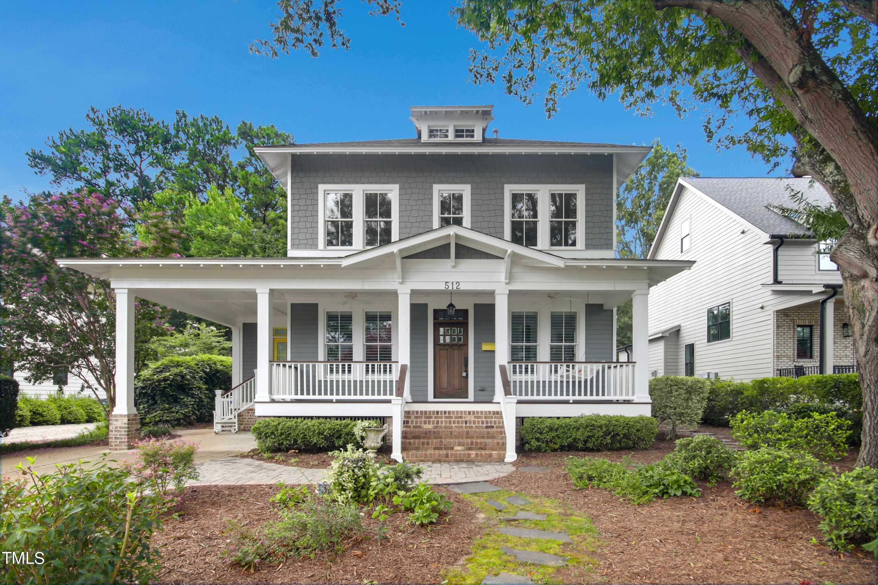 Gray two-story house with a broad white-columned porch, brick steps, and landscaped front garden.