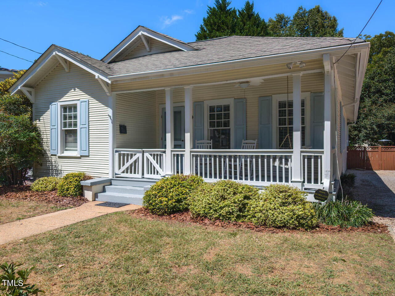 House exterior with a broad covered porch, white railings, and pale blue shutters.