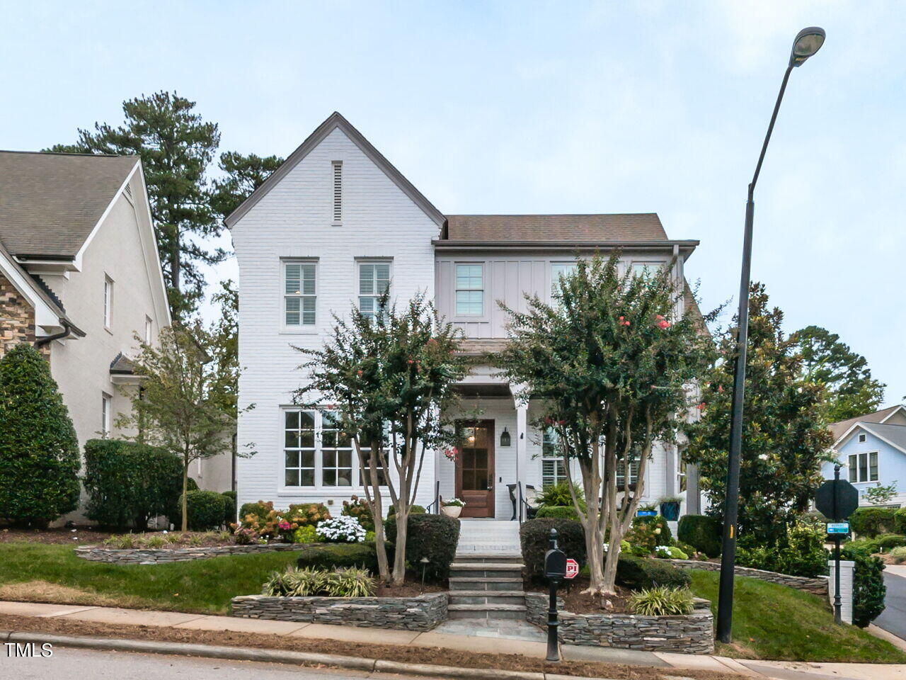 White two-story house with a prominent front gable, covered porch, and landscaped yard.