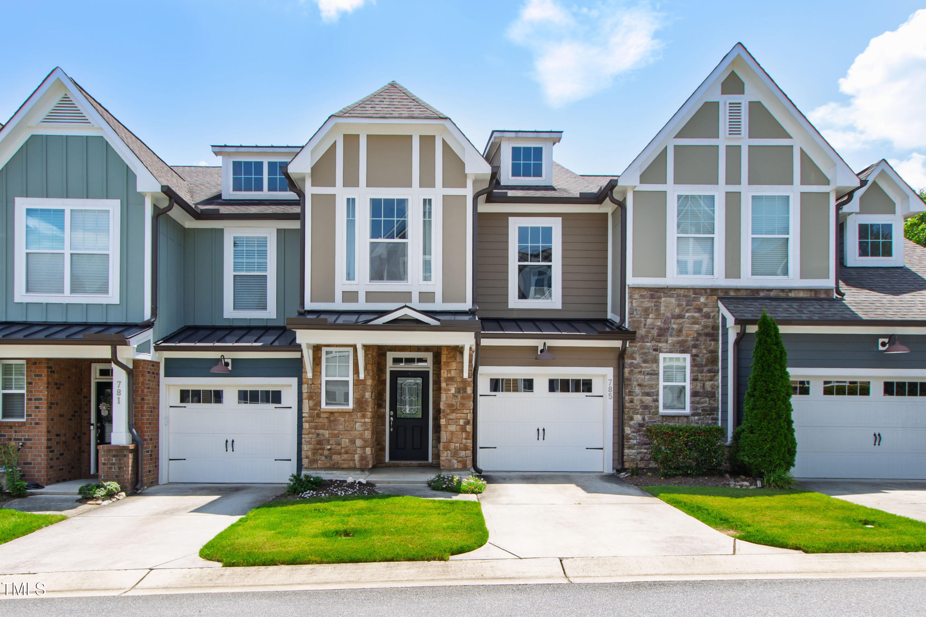 Attached two-story home with a stone entry, black front door, white garage, and steep gabled roof.