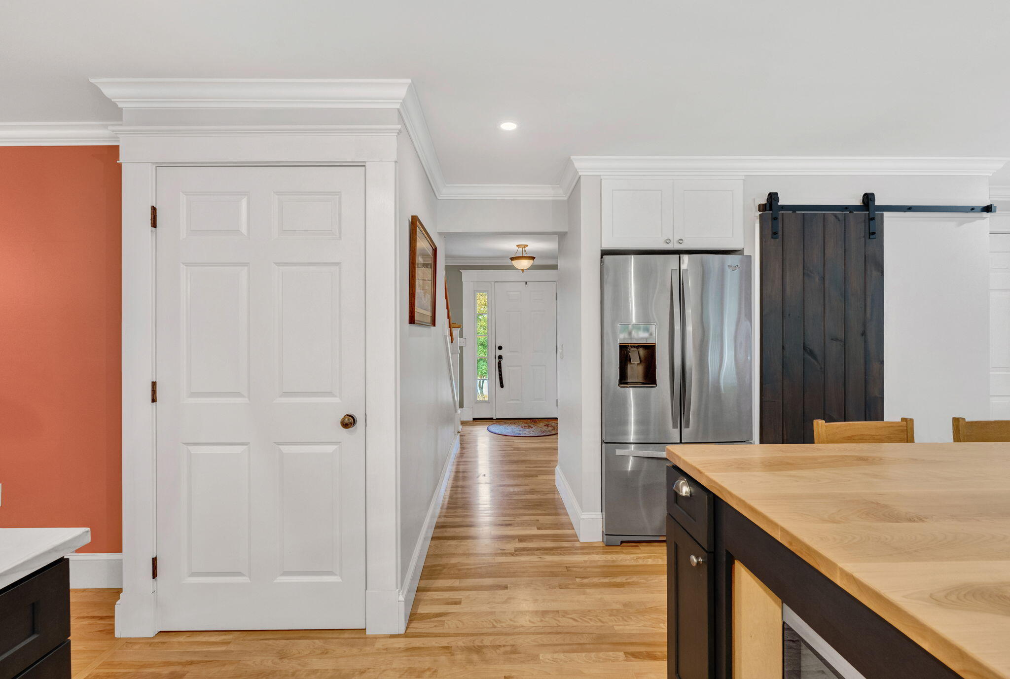 Kitchen with a wood-topped island, stainless steel refrigerator, and dark sliding barn door.