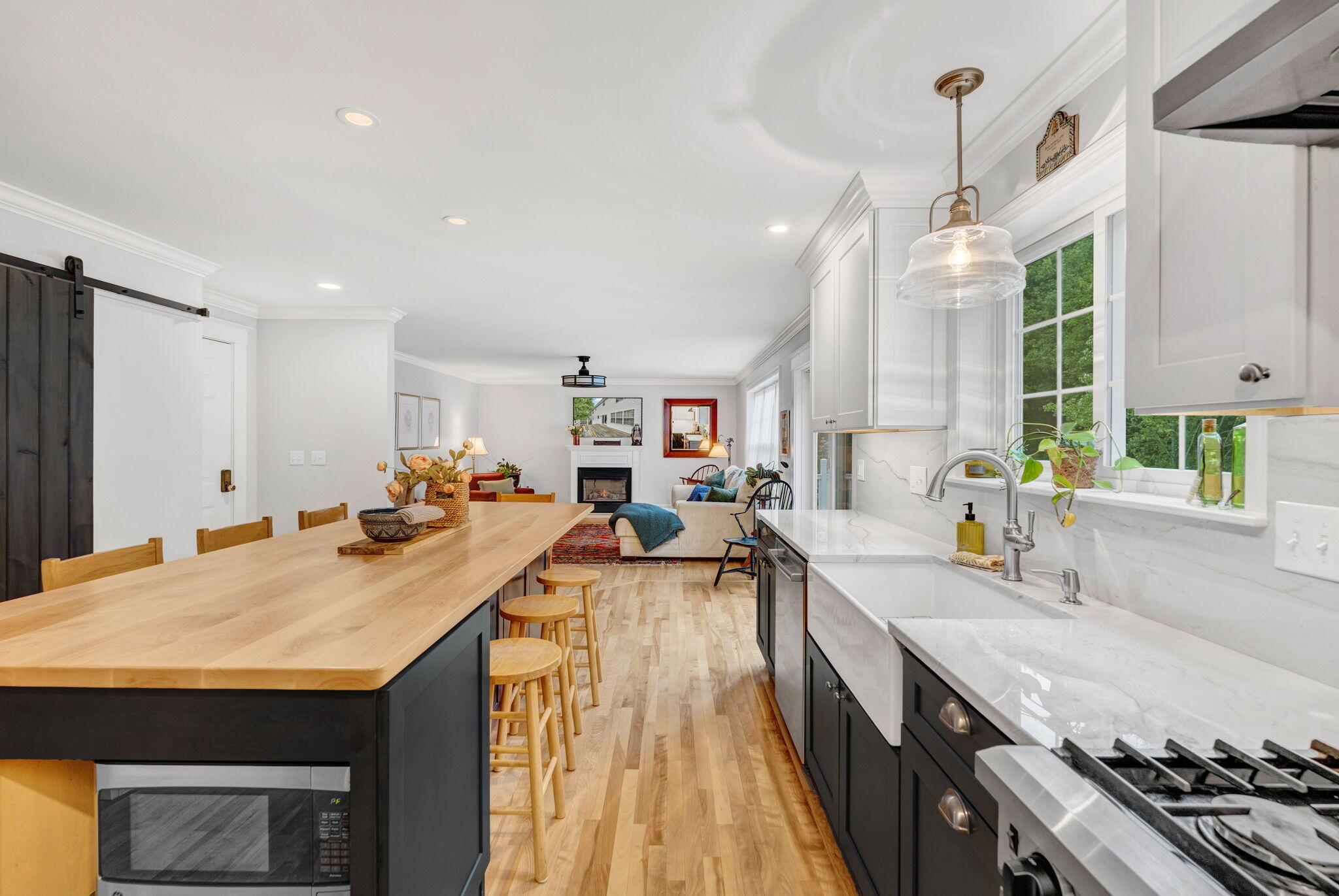 Open-plan kitchen with a wood-topped island, dark cabinets, and living area beyond.