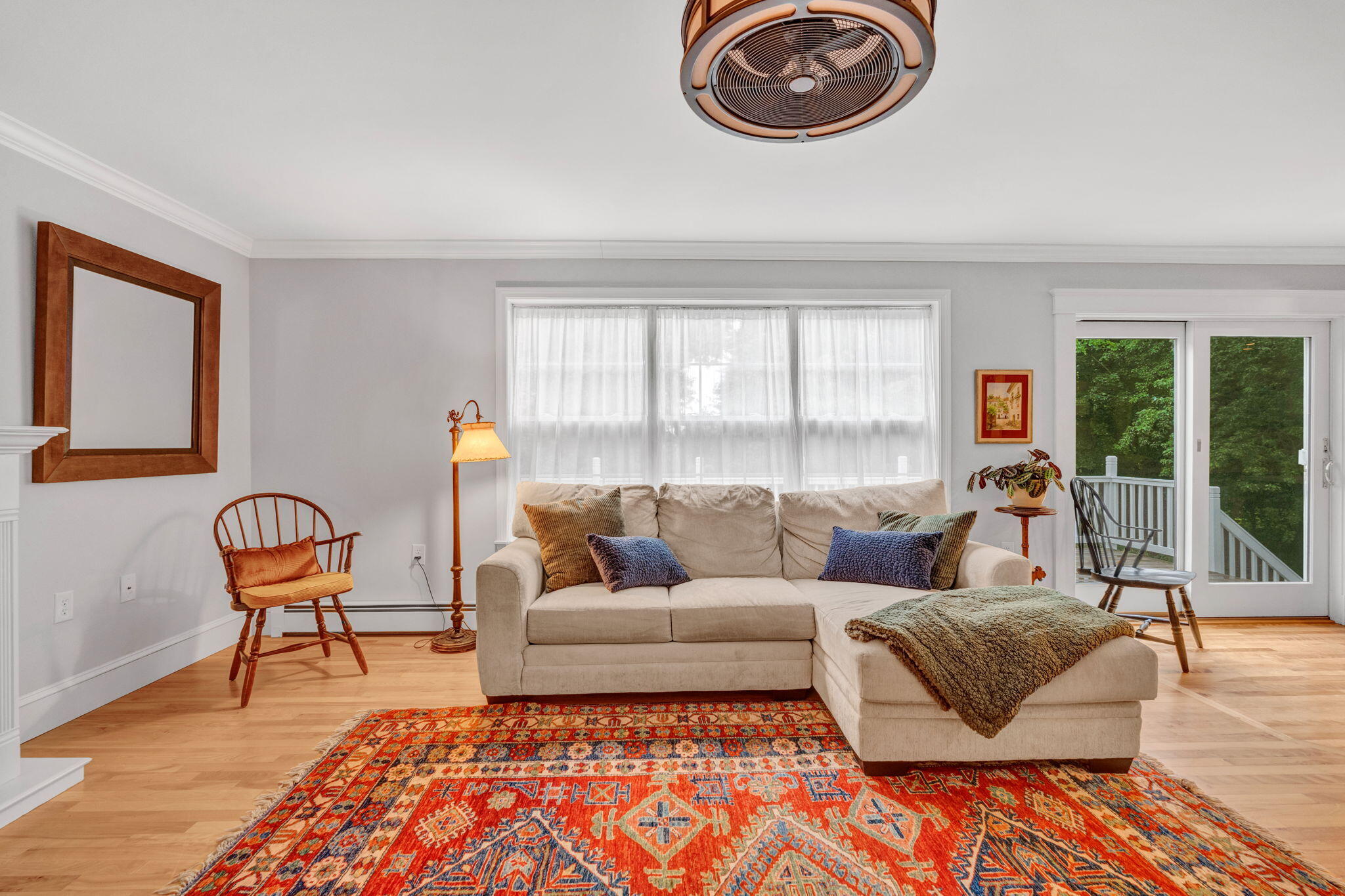 Living room with a beige sectional, colorful patterned rug, and sliding glass door to a deck.