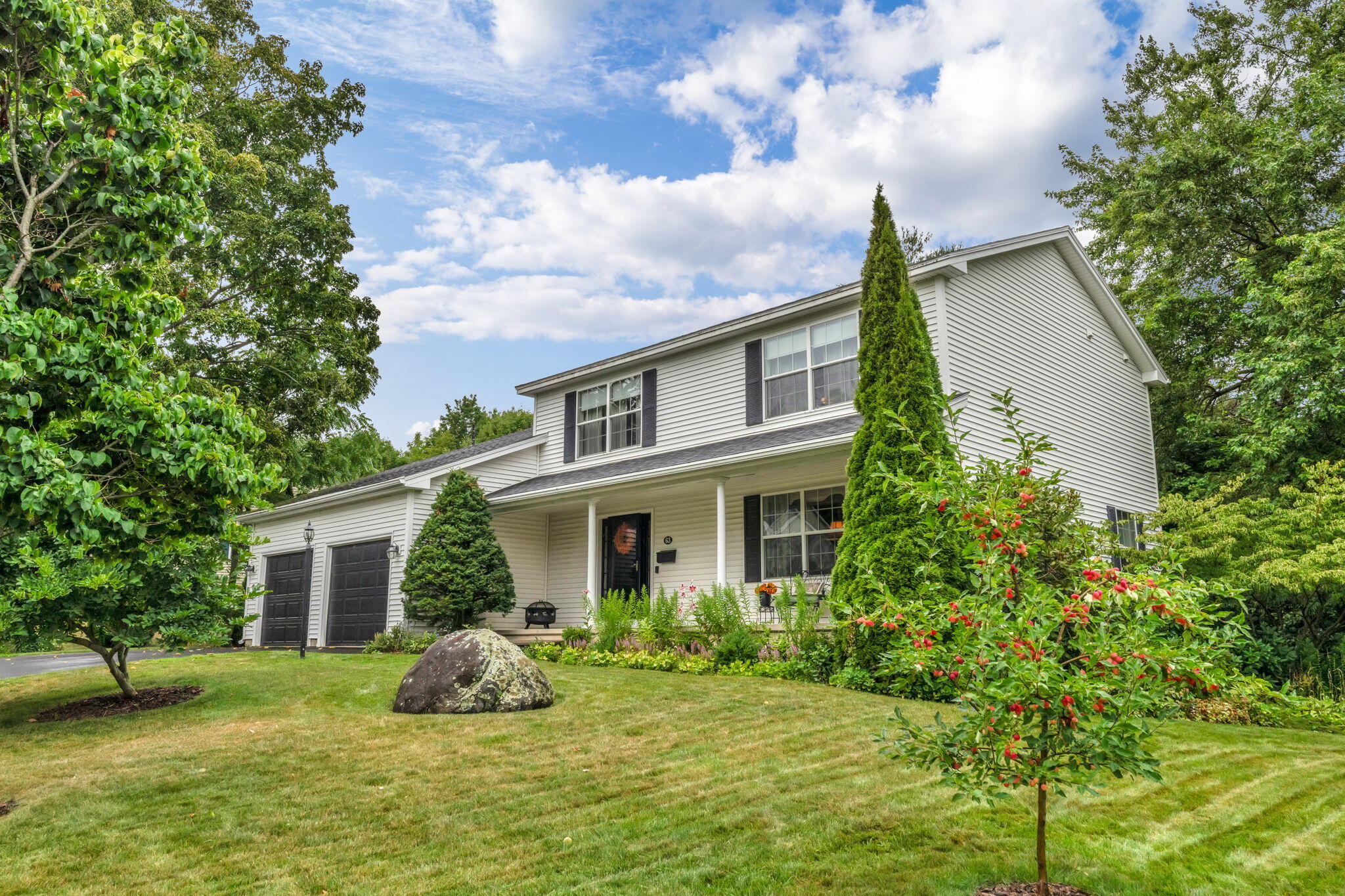 Two-story white house with an attached garage, covered porch, and landscaped yard.
