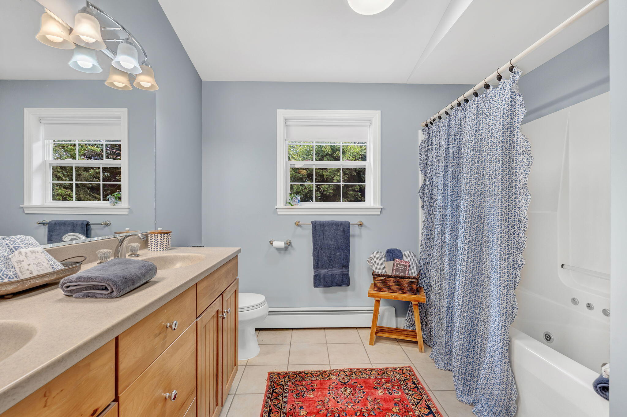 Bathroom with a wood vanity, jetted tub, and blue patterned shower curtain.
