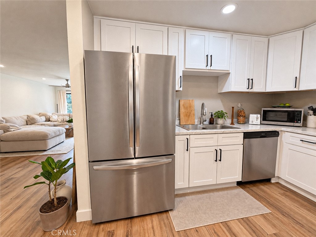 Kitchen with white shaker cabinets, stainless steel appliances, and an open view into the living room.