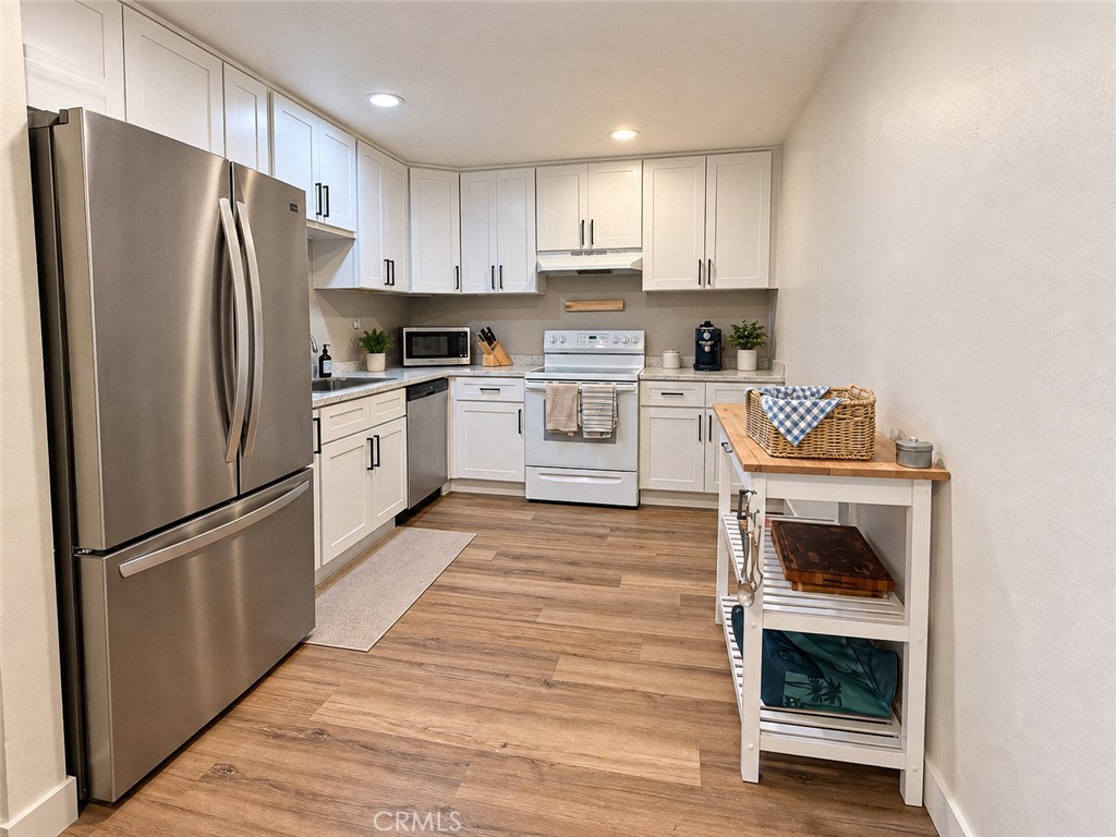 Kitchen with white cabinets, stainless steel appliances, and wood-look flooring.