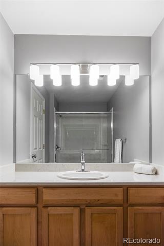 Bathroom vanity with wood cabinets, an oval sink, and a large mirror beneath bright lights.