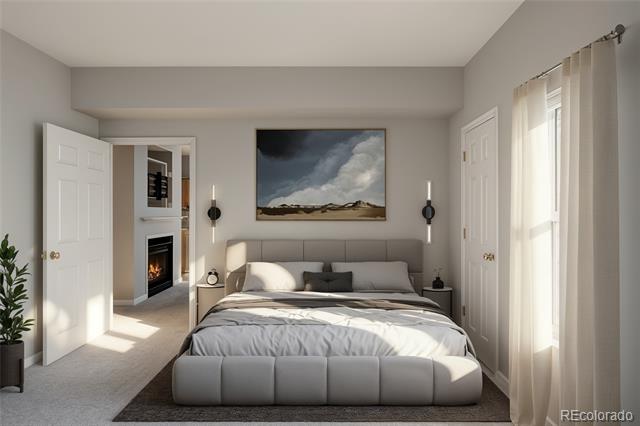 Staged bedroom with a gray upholstered bed, landscape artwork, and sunlight from a tall window.