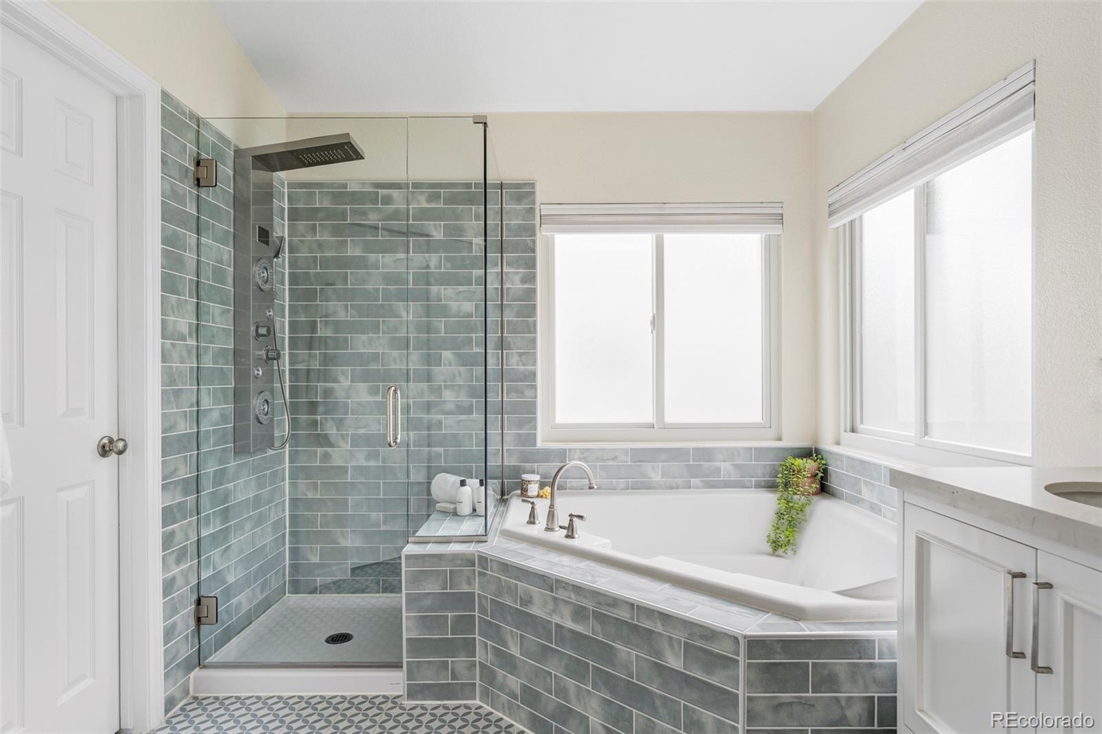 Bathroom with a tiled walk-in shower and soaking tub beneath two windows.