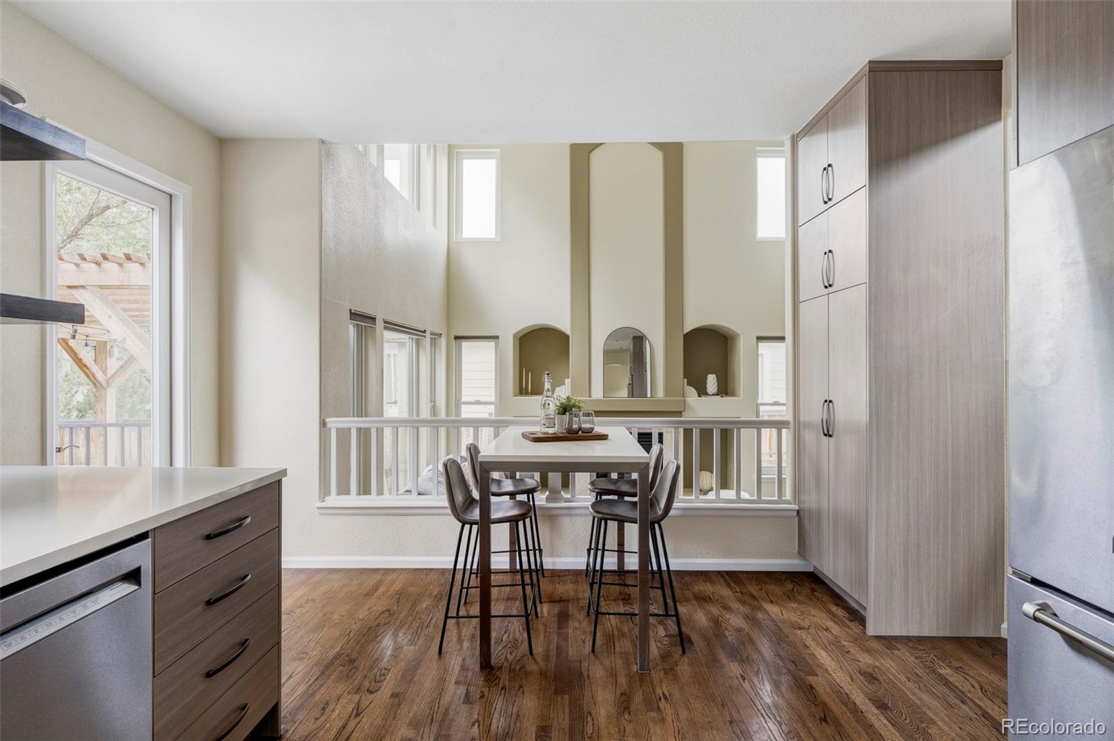 Kitchen with tall wood cabinetry, stainless steel appliances, and a dining table overlooking the lower level.