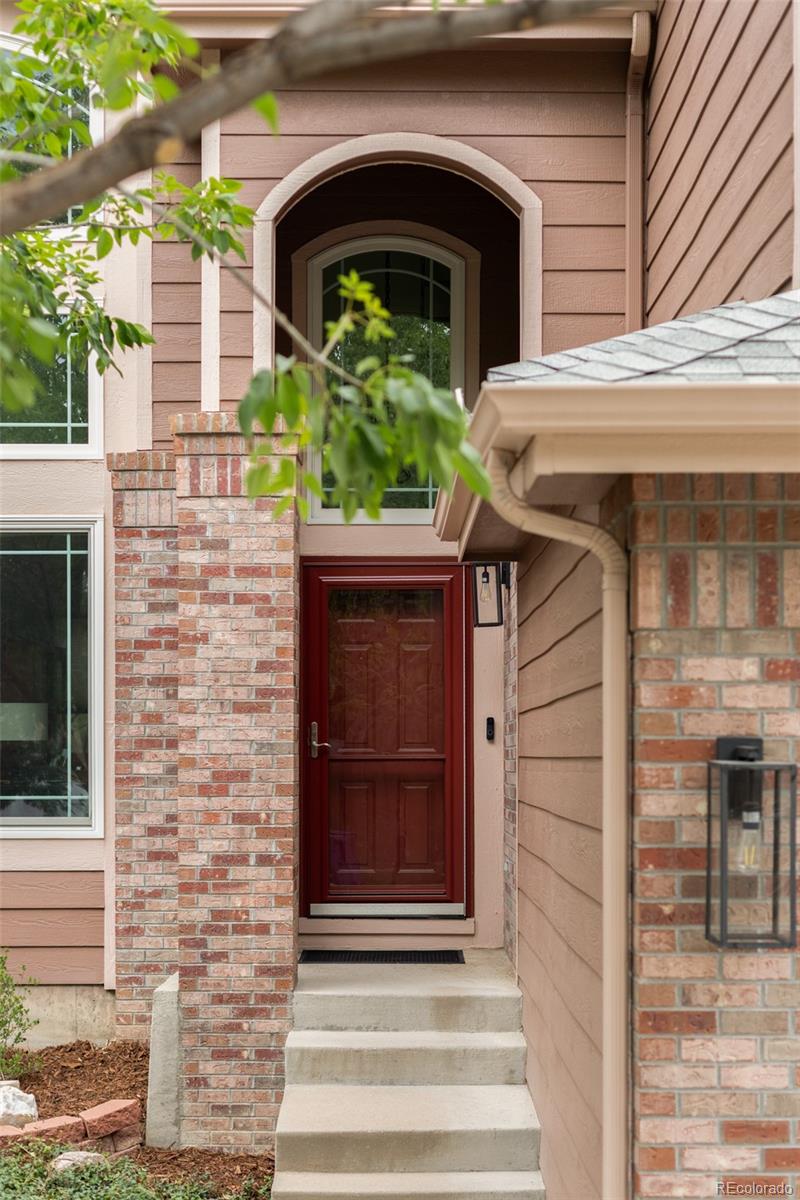 Home entrance with a red front door, brick columns, and concrete steps.