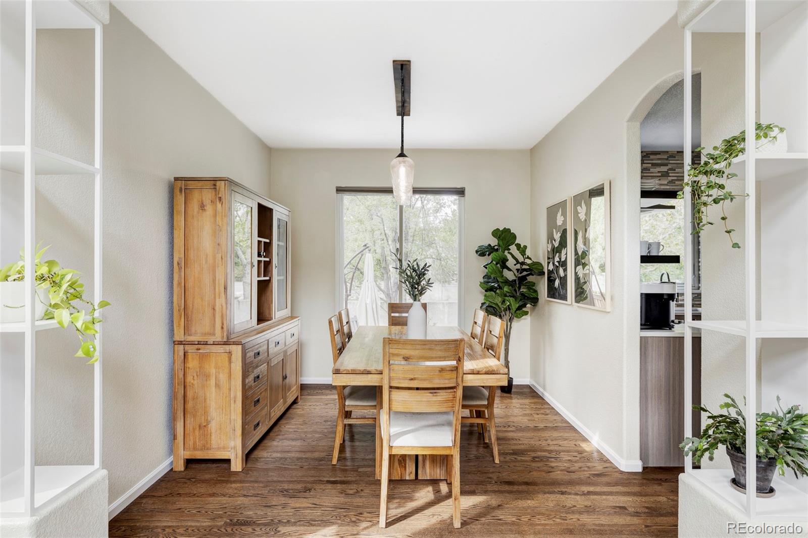 Dining room with a wooden table and hutch, hardwood floors, and an arched opening to the kitchen.