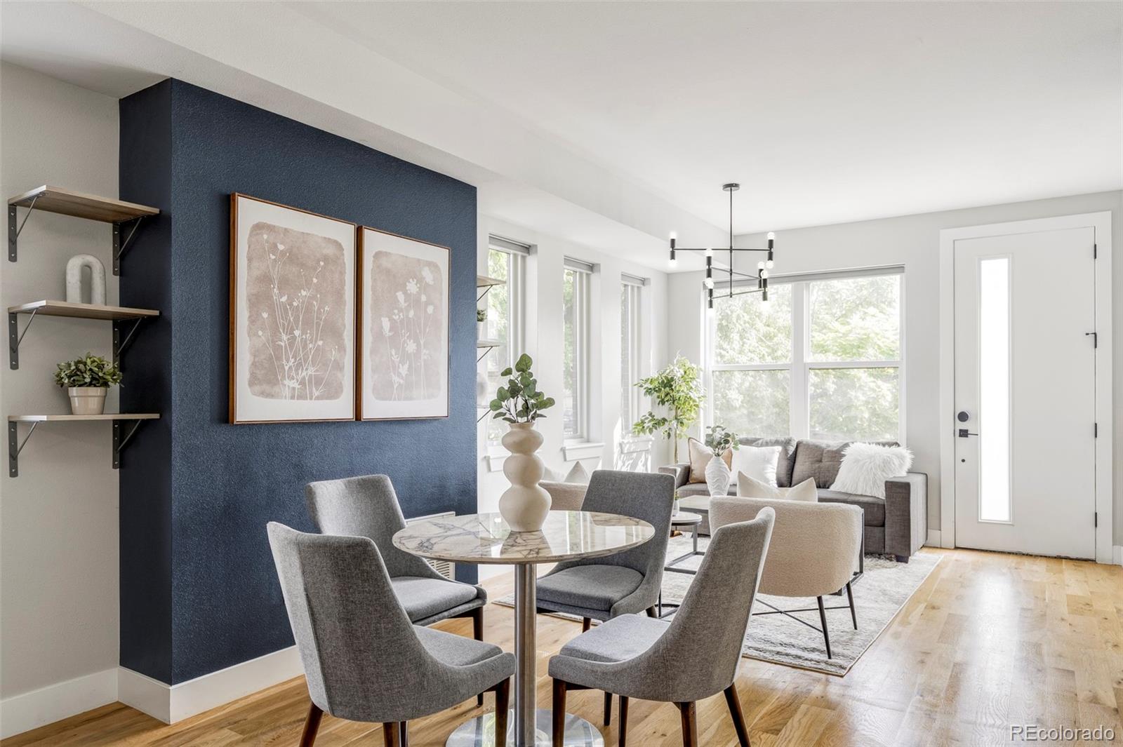 Dining and living room with a round marble table, navy accent wall, and large windows.