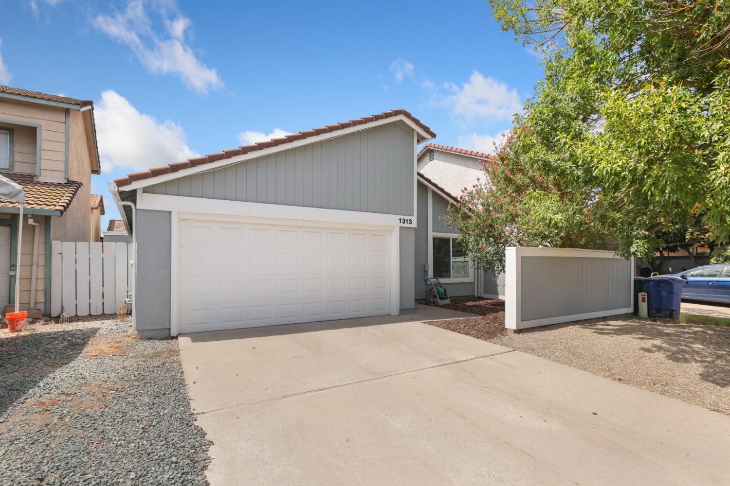Gray home with a wide white garage door, concrete driveway, and visible house number 1313.