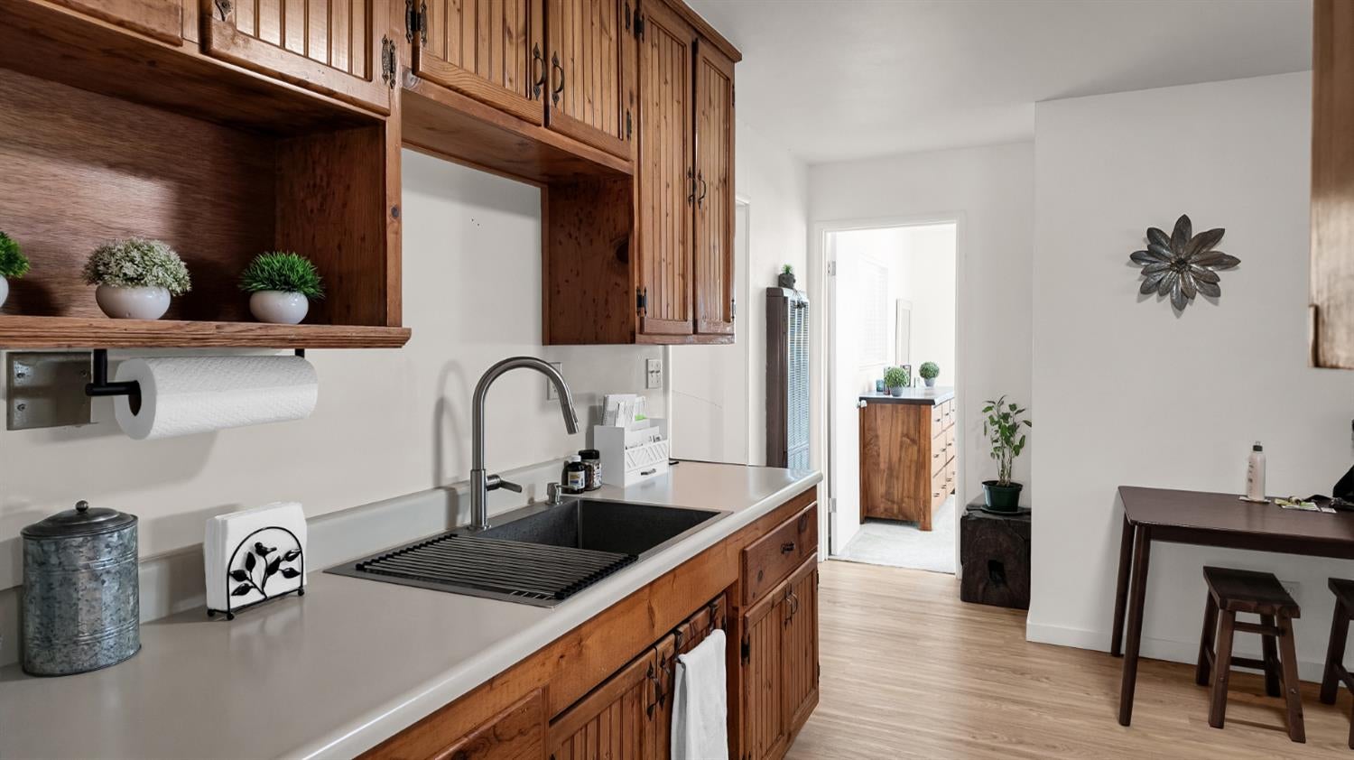 Kitchen with extensive wood cabinets, a long white countertop, dark sink, and adjoining dining area.