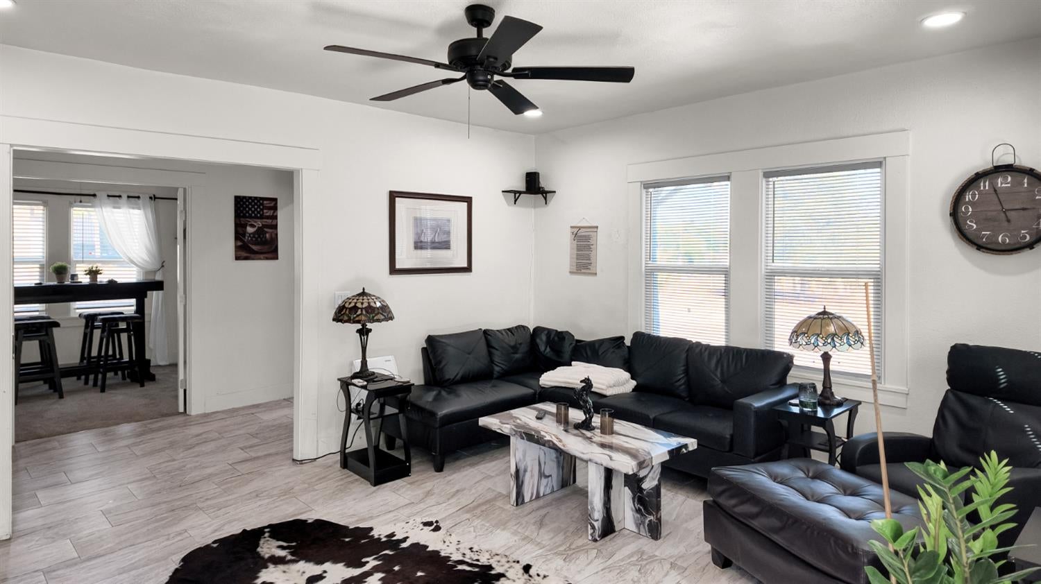 Living room with black leather seating, a marble-pattern coffee table, and a ceiling fan.